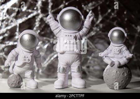 Trois jouets en plastique figurine astronaute sur fond argent espace de copie. Concept de voyage hors terre, vols commerciaux privés de spaceman. Missions spatiales et durabilité Banque D'Images