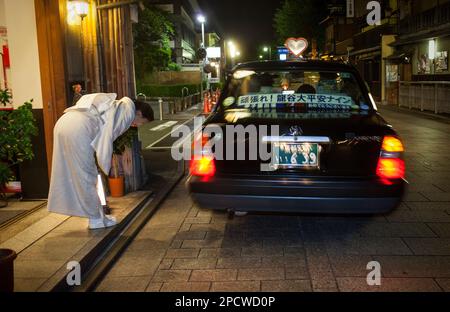 Oka san dit au revoir aux clients.Taxi dans Hanamikoji dori.Geisha de Gion du distric.Kyoto. L'aéroport du Kansai au Japon. Banque D'Images