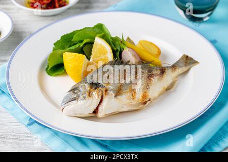 Dorade grillée avec légumes et légumes verts sur une table en bois Banque D'Images