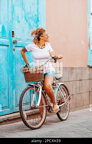 Une jeune femme adulte peut faire du vélo seul dans la rue. Porte bleue en arrière-plan. Femme regardant en arrière et à vélo seul. Lei extérieur printemps Banque D'Images