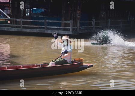 Pattaya, Thaïlande - 21 décembre 2022: Marché flottant de Pattaya, un vieil homme asiatique portant un chapeau, un masque médical, des lunettes de soleil dans un bateau, l'homme saluant Banque D'Images
