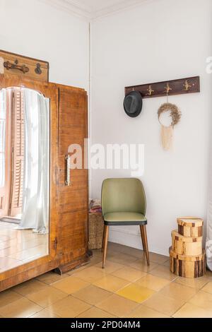 Cette chambre blanche dispose d''un mobilier élégant, d''une armoire en bois avec miroir, d''un fauteuil et d''un cintre avec des boîtes et du carrelage. Concept rustique de style vintage Banque D'Images