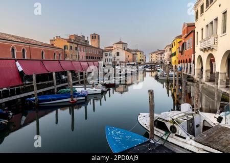 Chioggia,Vénétie,Italie, 05 mars 2023 : Chioggia paysage urbain dans la lagune de Venise avec étroit canal d'eau de Vena avec des bateaux colorés parmi les anciens bâtiments Banque D'Images