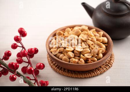 Grains de cacahuètes aromatisés épicés dans un bol sur fond de table blanc. Banque D'Images