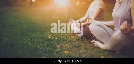 Deux femmes assises en tenue active en position lotus dans la nature. Banque D'Images