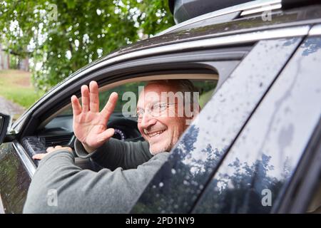 Portrait d'un homme âgé heureux en passant la main à travers la fenêtre tout en conduisant la voiture pendant les vacances Banque D'Images