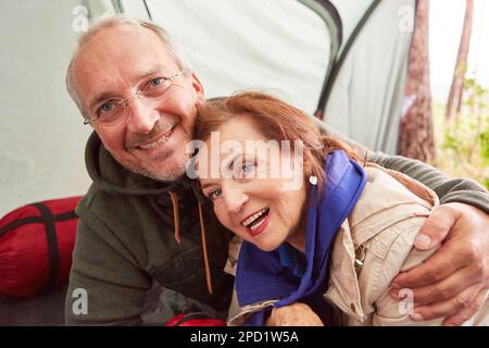 Portrait d'un couple senior heureux se relaxant dans une tente de camping en forêt pendant les vacances Banque D'Images