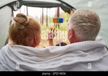 Un homme âgé emportant un selfie avec une femme sur un téléphone intelligent tout en enveloppant dans une couverture à l'intérieur d'une tente Banque D'Images