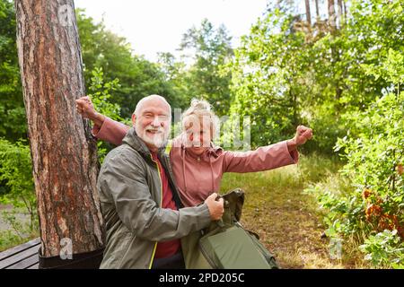 Portrait d'un couple senior joyeux assis en forêt pendant les vacances d'été Banque D'Images