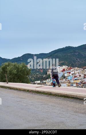 Homme marchant sur un trottoir dans une vieille ville de montagne marocaine Banque D'Images