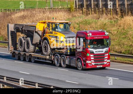 CYMRU AM BYTH KIERON M OWEN TRANSPORT LTD, CAERSWS, POWYS. Transport routier et services de transport. SCANIA R650 STGO CAT2. CAMION-benne VOLVO A30G sur une remorque à chargeur bas articulé ; sur l'autoroute M6, Royaume-Uni Banque D'Images