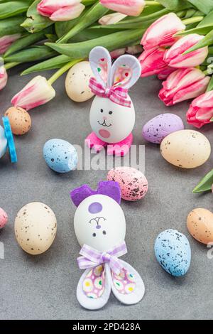 Plat de Pâques pond avec des lapins, des œufs et des tulipes mignons. Décor traditionnel, carte de vœux festive, concept de vacances, fond en béton de pierre grise, fermer u Banque D'Images