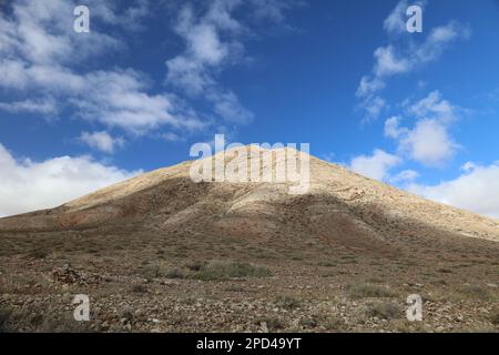 Vue panoramique de la montagne Sacrée 'Monntaña Sagrada de Tindaya' à Fuerteventura, avec un ciel bleu et une route vide Banque D'Images