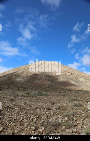 Vue panoramique de la montagne Sacrée 'Monntaña Sagrada de Tindaya' à Fuerteventura, avec un ciel bleu et une route vide Banque D'Images