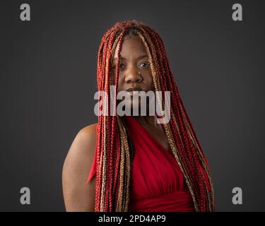 Portrait d'une jeune femme afro-américaine avec des tresses rouges sur fond noir Banque D'Images