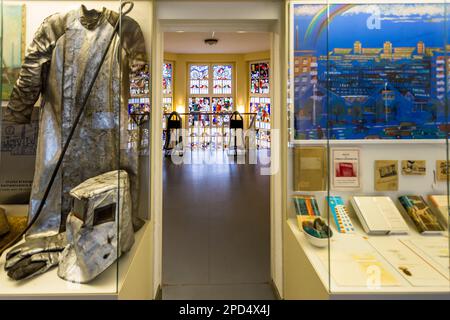 Musée Utopia et la vie quotidienne à Eisenhüttenstadt. L'exposition montre les facettes de la vie quotidienne dans la RDA dans la famille et le travail. Ici, vêtements d'un sidérurgiste de l'acier EKO (Eisenhütten Kombinat Ost). En arrière-plan, escalier avec vitraux de Walter Womacka (1955). Marchandises convoitées achetées en transit entre la RDA, la Pologne et la RSSC. Comme le travail du Mickerwork, la vaisselle Bunszlau ou les crayons de Pologne ou les films couleur et cassettes de musique de la RDA. Eisenhüttenstadt, Allemagne Banque D'Images