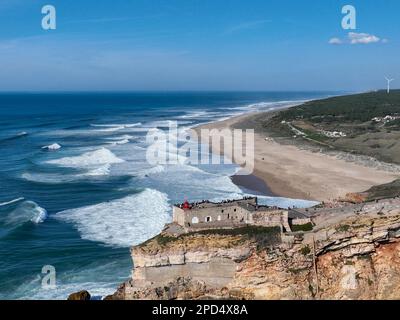 Phare à Nazaré, Portugal. Célèbre endroit pour les vagues et le surf. Plage et vagues de l'océan en arrière-plan Banque D'Images