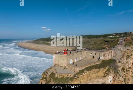 Phare à Nazaré, Portugal. Célèbre endroit pour les vagues et le surf. Plage et vagues de l'océan en arrière-plan Banque D'Images