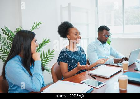 Une femme d'affaires fait des gestes ouverts pour discuter avec ses collègues dans la salle de réunion du bureau Banque D'Images