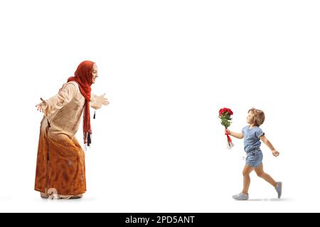 Fille avec des roses rouges courant vers une femme musulmane portant un hijab isolé sur fond blanc Banque D'Images