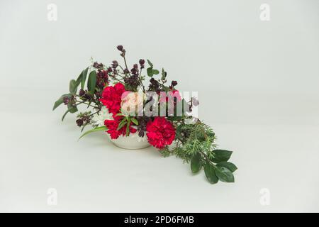 bouquet d'œillet rouge dans un vase sur fond blanc, isolé Banque D'Images