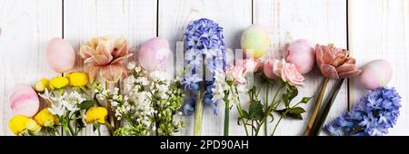 Bouquet printanier de jonquilles, jacinthes, roses, tulipes avec oeufs de pâques colorés sur fond blanc en bois. Concept joyeuses Pâques. Carte de vœux, interdiction Banque D'Images