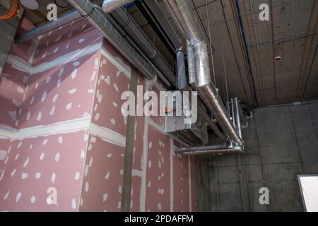 Système de chauffage et de refroidissement du bâtiment. Nouvelle installation de tuyauterie, montée sous le plafond près du mur en plaques de plâtre. Banque D'Images