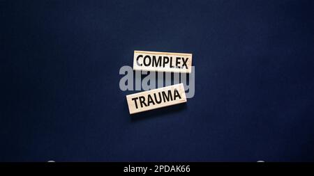 Symbole de traumatisme complexe. Concept mots trauma complexe sur bloc de bois. Beau tableau noir fond noir. Psychologie des affaires complexe traumatisme concep Banque D'Images