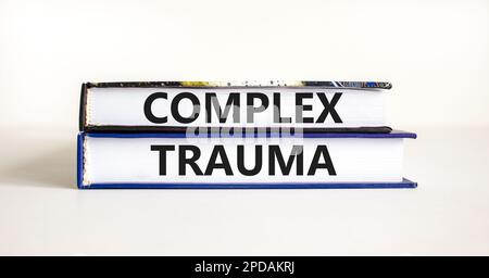 Symbole de traumatisme complexe. Concept mots trauma complexe sur les livres. Magnifique table blanche fond blanc. Psychologie des affaires concept de traumatisme complexe. Copier Banque D'Images