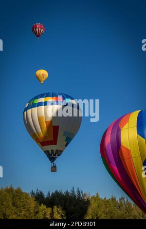 Quatre ballons à air chaud dans une ligne volant à différentes altitudes Banque D'Images