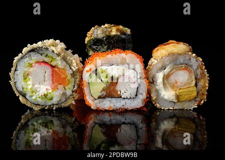 Rouleaux de sushis de différents types sur fond noir avec reflets Banque D'Images