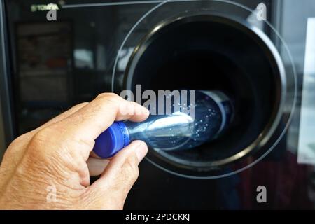 Symbolbild Rückgabeautomat für PET-Pfandflaschen - Männerhand wirft eine PET-Flasche in einen Automaten Banque D'Images