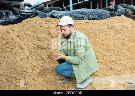 Les jeunes agriculteurs qui vérifient la qualité des brasseurs ont dépensé des grains en entreposage ouvert Banque D'Images