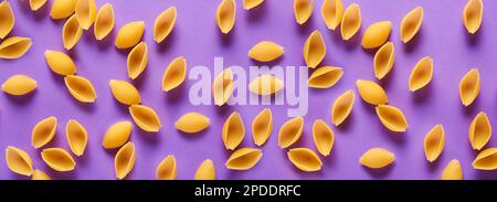 Séchez les pâtes conchiglie sur fond violet Banque D'Images