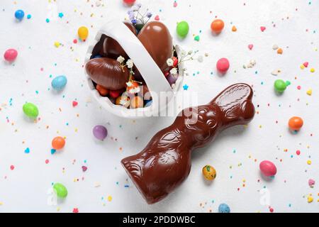 Lapin de Pâques au chocolat avec panier et œufs sur fond blanc Banque D'Images