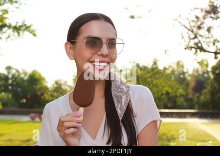 Belle jeune femme tenant de la glace émaillée de chocolat à l'extérieur Banque D'Images