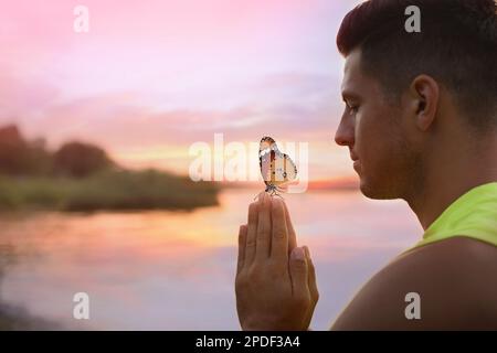 Homme méditant près de la rivière au coucher du soleil. Espace pour le texte Banque D'Images