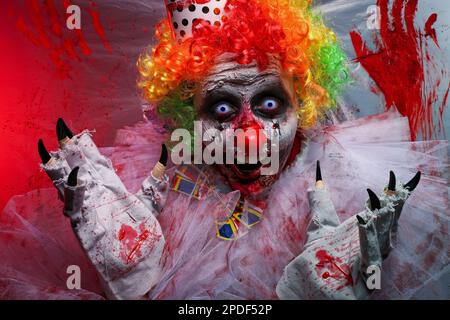 Un clown terrifiant près d'un film de plastique coloré par le sang. Costume de fête d'Halloween Banque D'Images