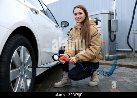 Jeune femme gonflant des pneus au service de voiture Banque D'Images