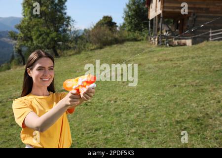 Bonne femme avec un pistolet à eau s'amusant dans les montagnes par beau temps Banque D'Images