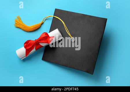 Chapeau de graduation et diplôme sur fond bleu clair, plat Banque D'Images