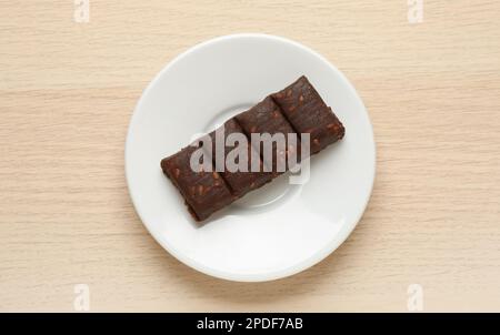 Assiette blanche avec bar hématogène délicieux et sain sur table en bois, vue de dessus Banque D'Images