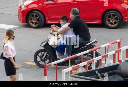 SAMUT PRAKAN, THAÏLANDE, 03 2023 FÉVRIER, Un homme roule avec un garçon en uniforme scolaire sur une moto. Banque D'Images