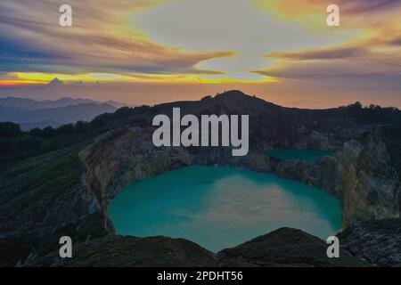 Lever de soleil avec ciel nuageux au-dessus du volcan Mont Kelimutu, en premier plan le lac bleu turquoise cratère. Banque D'Images