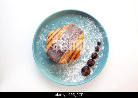 Croissant au chocolat brioche servi sur une assiette bleue. Banque D'Images