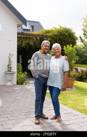 Portrait d'un homme biracial senior souriant, main sur l'épaule de la femme, debout sur le sentier dans la cour Banque D'Images