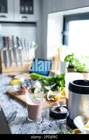 Gros plan du smoothie dans le verre à boire avec le mélangeur et les fruits sur le comptoir de la cuisine, espace de copie Banque D'Images