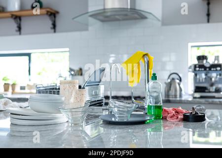 Gants de lavage jaunes sur le robinet avec vaisselle sale et distributeur de savon sur le comptoir de cuisine Banque D'Images