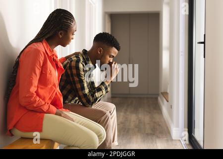 Triste couple afro-américain assis sur un banc en bois dans le hall Banque D'Images