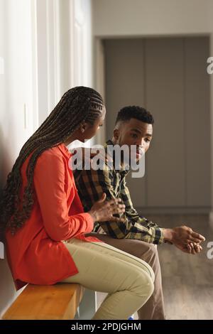 Triste couple afro-américain assis sur un banc en bois dans le hall Banque D'Images